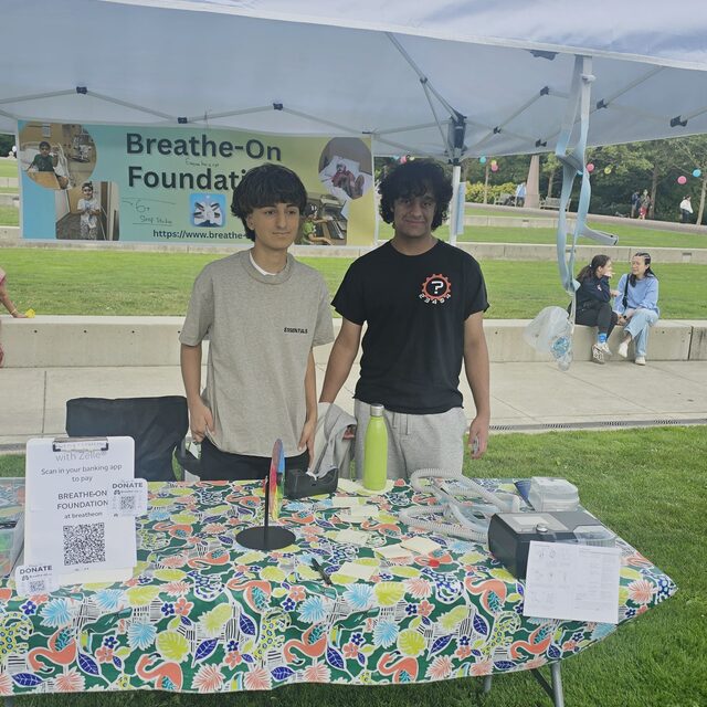 Two Breathe On youth leaders looking into the camera at their outreach table